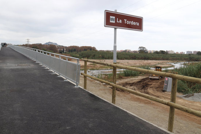 Pla general del vial per a vianants del nou pont sobre la Tordera amb el riu de fons i el cartell en primer terme el 6 de novembre de 2020 (Horitzontal)