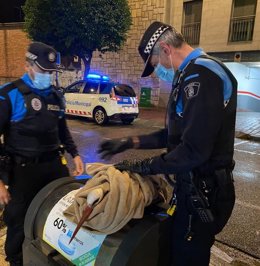 Dos agentes recogen a una cigüeña incapaz de volar por la lluvia.