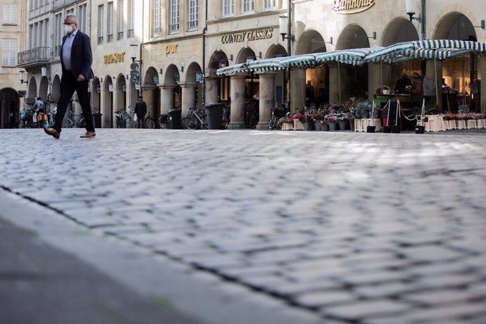 03 November 2020, North Rhine-Westphalia, Muenster: A man wears a face mask while walking across the almost deserted square at Prinzipalmarkt after the German government decided to put the country in four-weeks of partial lockdown in an attempt to slow 