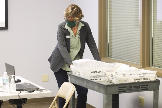 06 November 2020, US, Tampa: Peg Reese, Hillsborough County Supervisor of Elections Chief of Staff, brings in a collection of vote by mail ballots as they prepare to begin canvassing mail-in and provisional ballots at the Hillsborough Supervisor of Elec