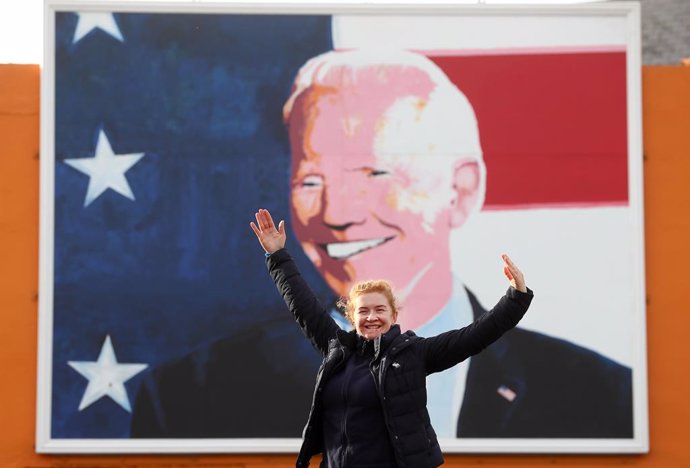 05 November 2020, Ireland, Ballina: Maria Bourke, from Knockmore, poses for a photograph under a mural of US Presidential candidate Joe Biden in his ancestral home of Ballina where he visited in June 2016 as US Vice President. Photo: Brian Lawless/PA Wi