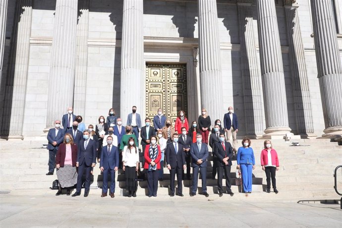 Fotografía conjunta de los miembros de la Comisión de seguimiento y evaluación del Pacto de Toledo, frente al Congreso de los Diputados