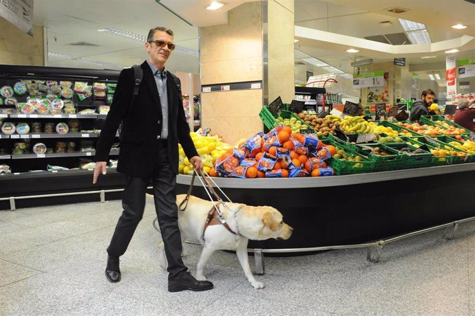 Persona ciega con perro guía en supermercado