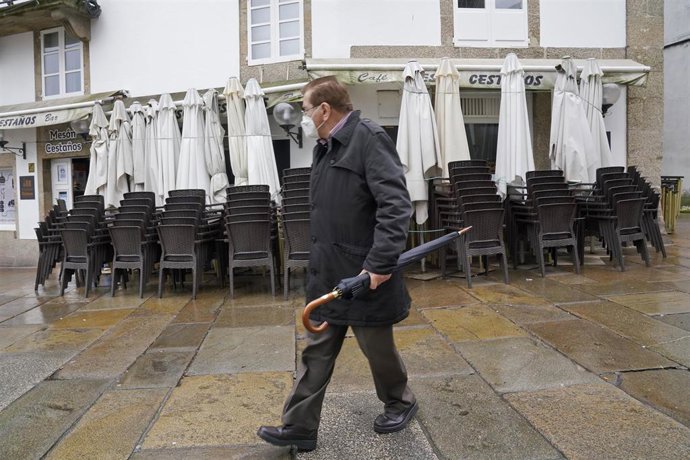 Un hombre pasa al lado de una terraza recogida en un establecimiento durante el primer día de cierre en la hostelería decretado debido a la crisis del Covid-19, en Santiago de Compostela, Galicia, (España), a 7 de noviembre. La hostelería permanece cerr