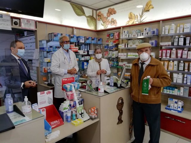 La delegada de Salud en Jaén, Trinidad Rus, y el presidente del Colegio de Farmacéuticos, Juan Pedro Rísquez, este domingo en la entrega de un lote de tres mascarillas a un usuario.