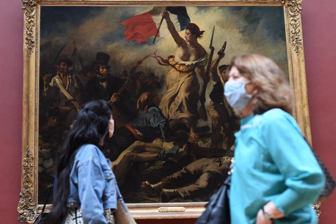 Una mujer con mascarilla frente al cuadro 'La libertad guiando al pueblo' de Eugne Delacroix, en el Museo del Louvre de París