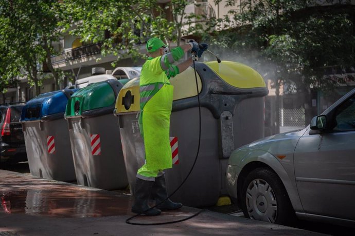 Un operario de limpieza del servicio municipal desinfecta un contenedor amarillo de basura tras la reincorporación de 1.000 operarios de limpieza durante la fase 0 de la desescalada en la ciudad. Como anunció el concejal de Emergencia Climática y Transi