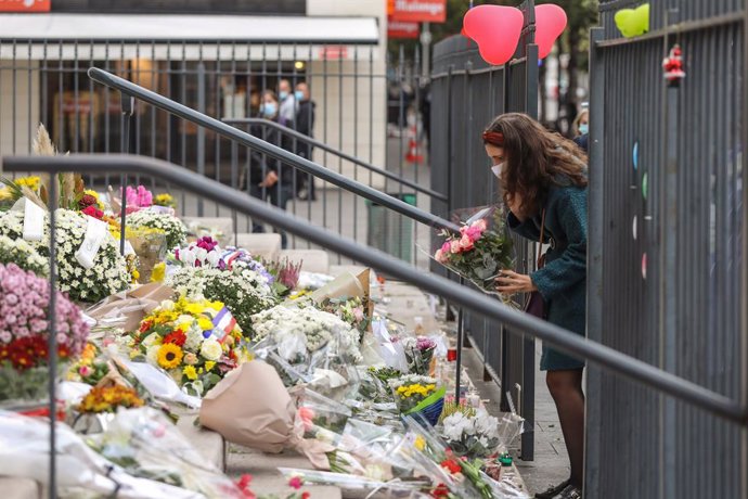31 October 2020, France, Paris: A woman lays flowers on the steps of the Basilica Notre-Dame for the victims of a knife attack in Nice. Photo: Valery Hache/AFP/dpa