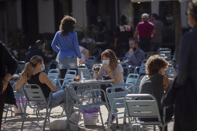 Varias personas en la terraza de un bar, el día que entra en vigor la modificación de la orden de 14 de julio que regula el uso de mascarillas en Andalucía, aprobada este jueves por el Consejo de Gobierno de la Junta para frenar el avance de los contagi