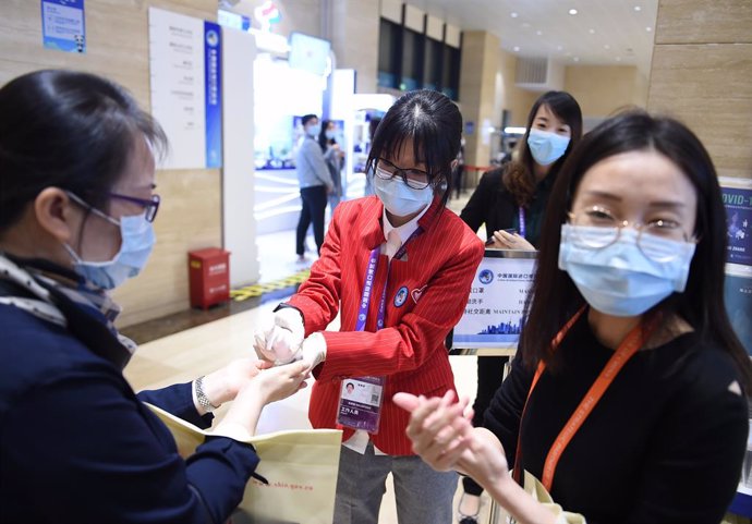 Un grupo de personas se desinfecta las manos con gel durante un evento de exposiciones en Shanghái.