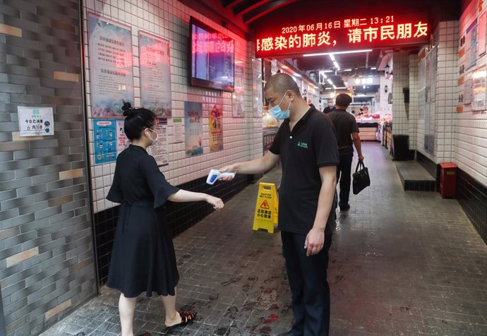 Una mujer se somete a una prueba de temperatura antes de poder entrar a un mercado de verduras en Shanghái, en el este de China.