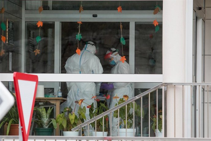 Dos trabajadores sanitarios totalmente protegidos acuden a la residencia de ancianos de San Cibrao donde se ha originado un brote de Covid-19, en San Cibrao, Lugo.