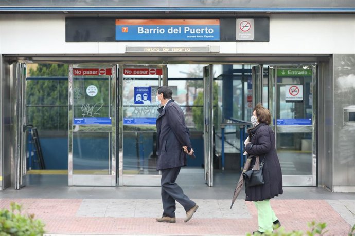 Dos personas pasan al lado de una de las puertas del metro Barrio del Puerto, en la zona básica de salud de Doctor Mamames, en Coslada