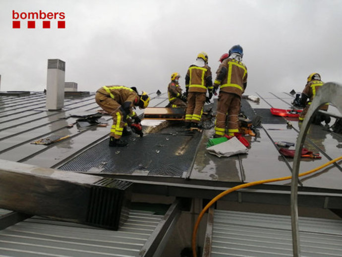 Pla mitj dels Bombers treballant a la teulada de l'edifici afectat a Girona aquest dissabte 7 de novembre de 2020. (Horitzontal)