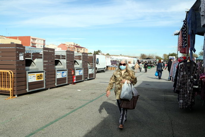 Pla general d'una dona caminant per davant d'una de les illes de contenidors de recollida selectiva al mercat de Bonavista de Tarragona. Imatge del 8 de novembre del 2020 (Horitzontal).