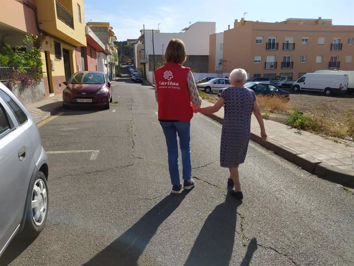 Una voluntaria de Cáritas Diocesana de Tenerife acompaña a una anciana