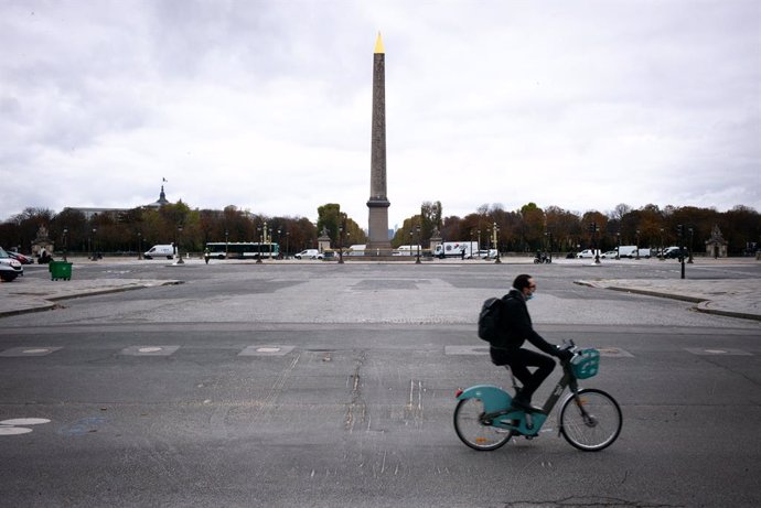 30 October 2020, France, Paris: A man rides a bicycle at the deserted Place de la Concorde square, as France goes into coronavirus lockdown for the second time this year from today, Friday, until 1 December 2020 to curb the spread of the coronavirus pan