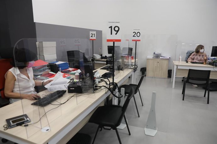 Dos trabajadoras de la Oficina del Empleador protegida con mascarilla y con una pantalla separadora en su mesa durante la visita del vicepresidente, consejero de Deportes, Transparencia y portavoz del Gobierno de la Comunidad de Madrid, Ignacio Aguado, 