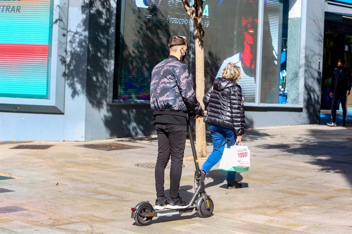 Un joven pasea en patinete por la céntrica calle de Fuencarral, en Madrid.