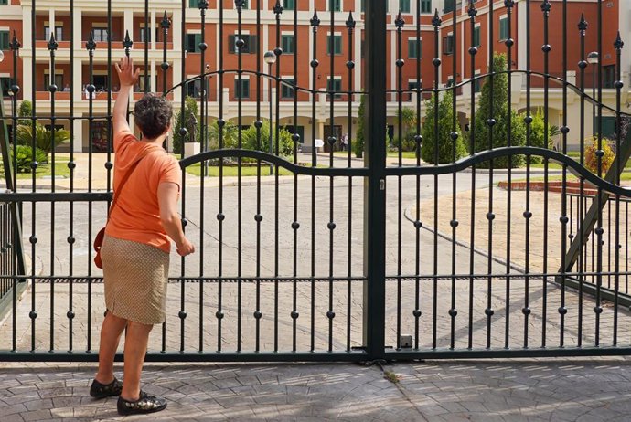 Una señora saluda desde la reja a un familiar en la residencia de ancianos de San Juan de Dios después de que la Junta de Andalucía permita visitar durante una hora a mayores en residencias. Sevilla a 02 de mayo del 2020