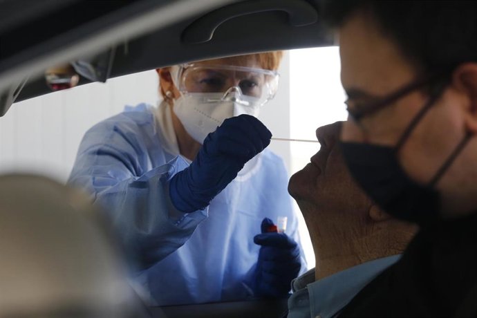 Una enfermera toma muestras para una PCR a un paciente en un coche.