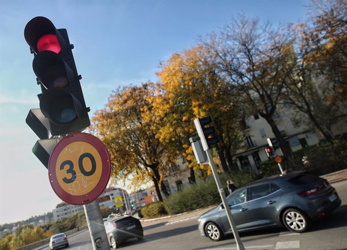 Varios coches circulan al lado de una señal de tráfico en una vía de la capital el mismo día en que han aprobado la reducción de la velocidad hasta 20km/h en las ciudades y la pérdida de seis puntos por usar el móvil, en Madrid, (España), a 10 de noviem