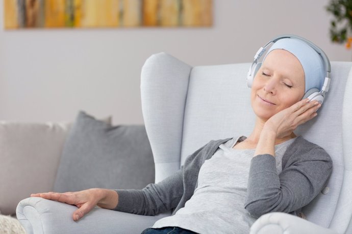 Mujer con cáncer escuchando música. Músicoterapia.