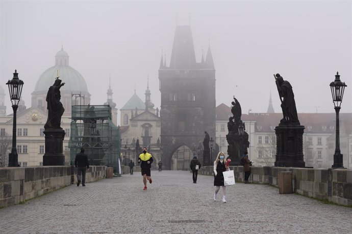 Personas con mascarilla recorriendo un puente de Praga