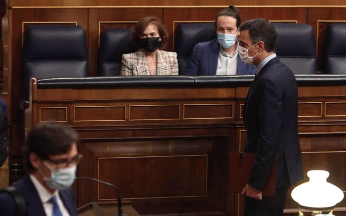 El presidente del Gobierno, Pedro Sánchez, pasa por delante la vicepresidenta primera del Gobierno, Carmen Calvo, y el vicepresidente segundo del Gobierno, Pablo Iglesias, durante una sesión de control al Gobierno en el Congreso de los Diputados, en Mad