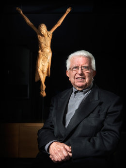 Pla mig del mossn Jesús Tarragona, amb un crist al darrere. Imatge d'arxiu. (Vertical)