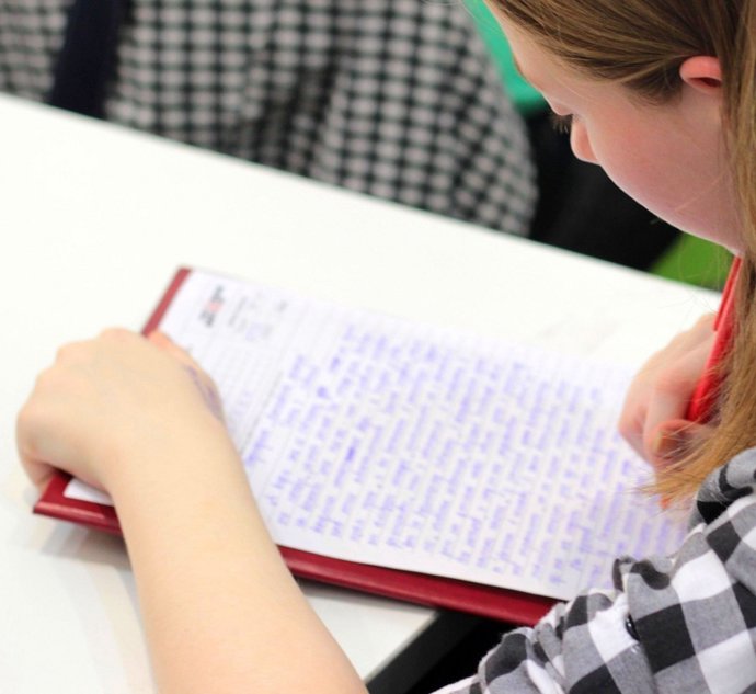 Alumna escribiendo en un centro escolar.