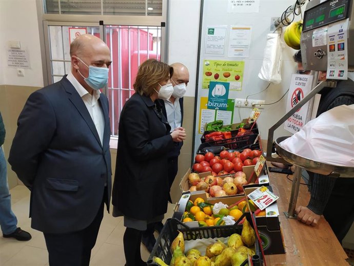 Susana Díaz, entre Antonio Ruiz y Rafael Bados, hablan con un pequeño comerciante.
