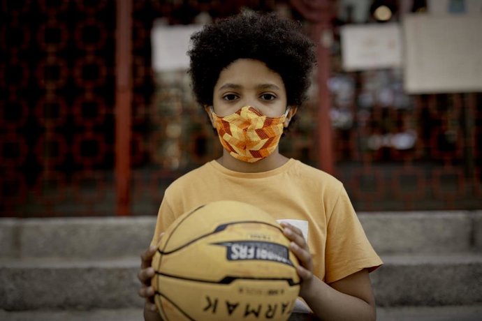Niño posa con una pelota de baloncesto