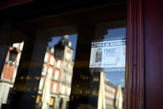 Décimo del Sorteo Extraordinario de la Lotería de Navidad 2020 pegado en el escaparate de un restaurante de la Plaza Mayor