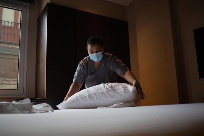 Una camarera de pisos cambia las sábanas de una cama 