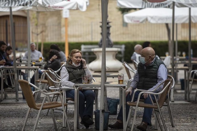Personas consumiendo en los veladores de un bar abierto