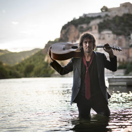 Pla americ del músic i cantant miravet ric Vinaixa amb la seva guitarra dins del riu Ebre. (vertical)
