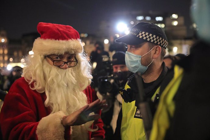 05 November 2020, England, London: A costumed man speaks with a policeman during the Million Mask March anti-establishment protest at Trafalgar Square on the first day of a four week national lockdown for England. Photo: Aaron Chown/PA Wire/dpa