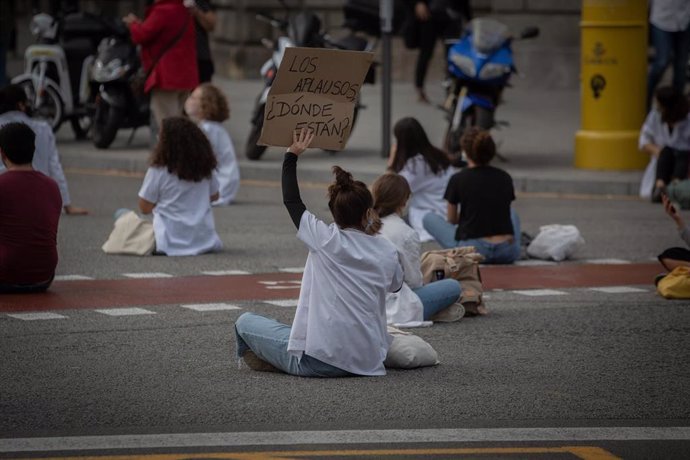 Una profesional sanitaria sostiene un cartel en el que se lee '¿Dónde están ahora los aplausos?' sentada en el suelo de la Calle de Balmes con Gran Via de les Corts Catalanes en una nueva concentración de Médicos Internos Residentes (MIR) en Barcelona, 