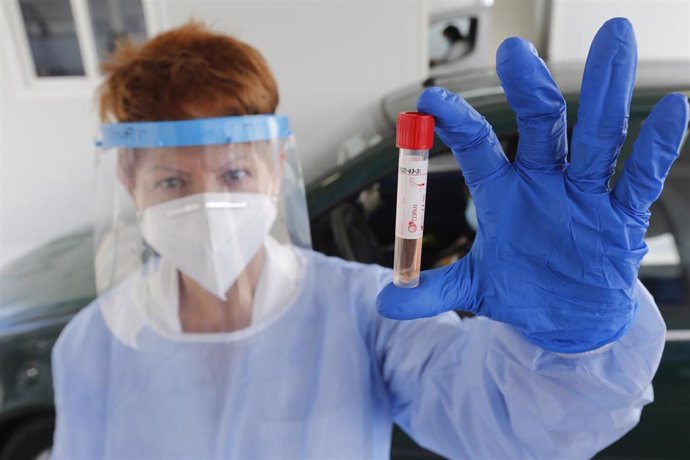 Una enfermera muestra un tubo de un test PCR.