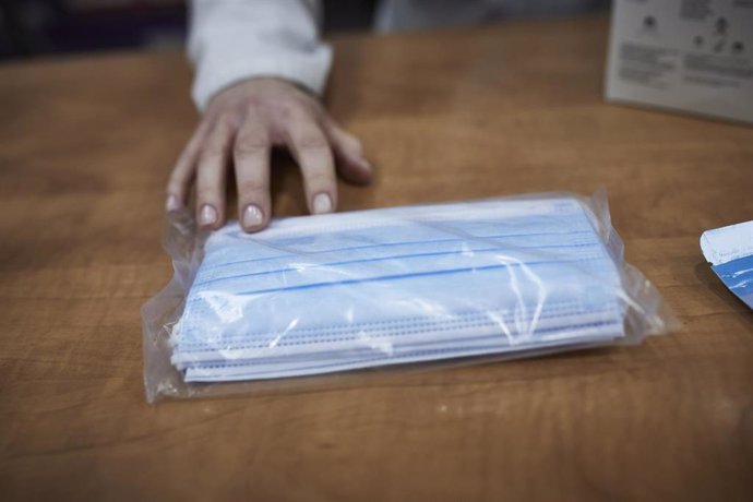 Una farmacéutica enseña a un cliente un paquete de mascarillas en la farmacia situada en la calle Tucán, 7, en el distrito de Carabanchel, Madrid (España), a 11 de noviembre de 2020. El Gobierno ha anunciado hoy que el Consejo de Ministros aprobará el m