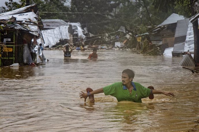 Un hombre camina hundido hasta los hombros debido a una inundación causada por el huracán 'Vamco'