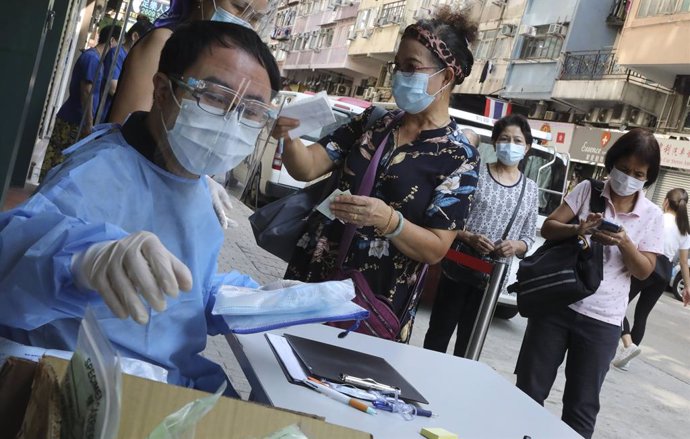Personal médico de un centro hospitalario de Hong Kong atiende a un grupo de personas que se van a someter a la prueba de coronavirus.