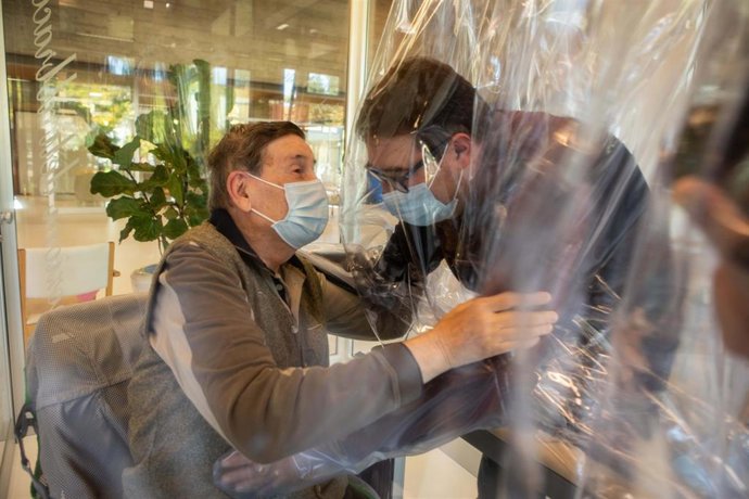 11 November 2020, Italy, Castelfranco Veneto: A resident (L) of the Domenico Sartor nursing home in Castelfranco Veneto embraces a visiting relative through a protective plastic sheet in a so-called "Hug Room" amid the new coronavirus pandemic. Photo: F