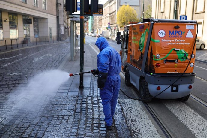 24 March 2020, Poland, Krakow: A worker sprays disinfectant towards a street as a preventive measure against the Coronavirus (Covid-19) outbreak. Photo: Filip Radwanski/SOPA Images via ZUMA Wire/dpa