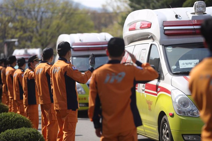 02 April 2020, South Korea, Daegu: Rescue workers in virus-hit Daegu wave toward ambulences carrying their colleagues temporarily mobilized from other areas as they return to their original workplaces after completing their months-long mission to transp