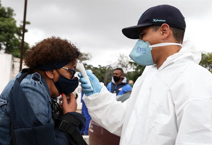 Un sanitario toma la temperatura a una mujer en Sao Paulo.