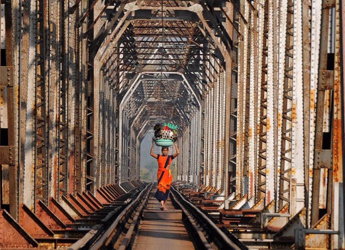 Una mujer pasa sobre una vía de tren en Bombay