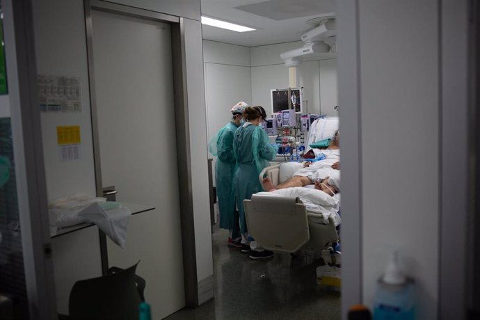 Personal sanitario visita a un enfermo ingresado en la Unidad de Cuidados Intensivos del Hospital de la Santa Creu i Sant Pau (Archivo)