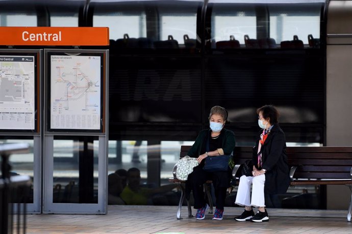 Dos personas con mascarilla esperando al transporte público en Sídney, donde ya no es obligatorio el uso de la mascarilla